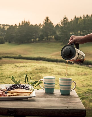 Unwind in Northland accommodation | Morning coffee overlooking rolling olive grove hills in New Zealand