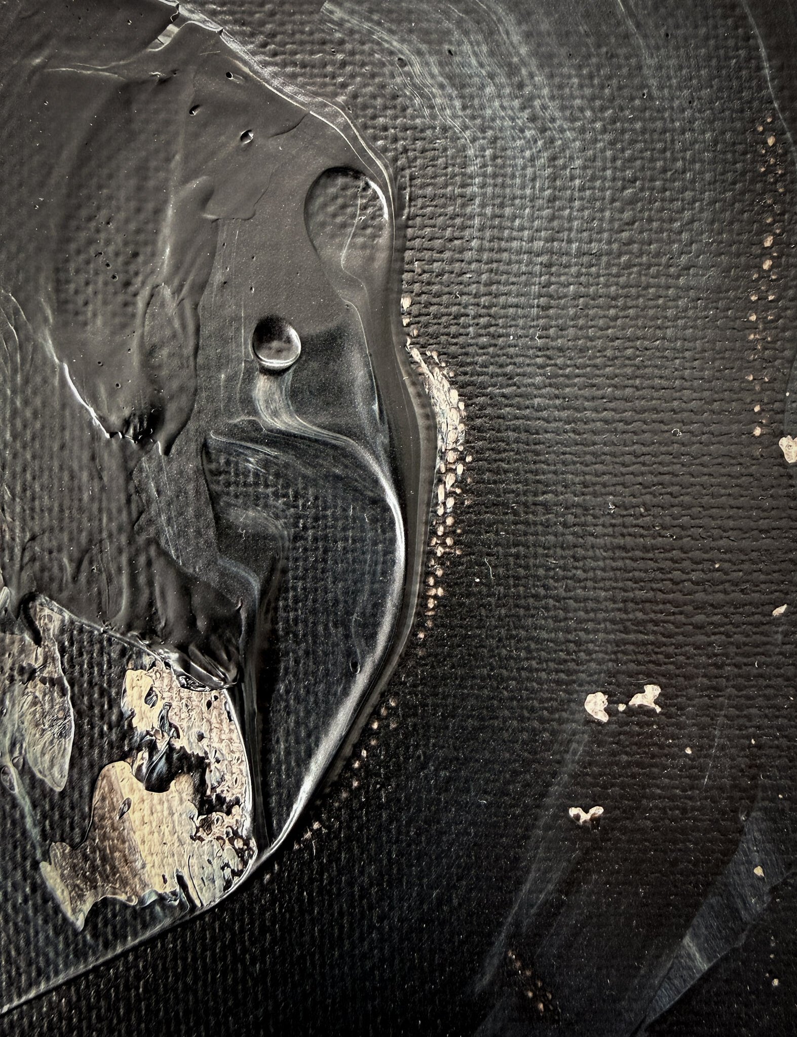 detail image of black and pale cream abstract painting, showing impasto ridge with pooled edge, small air bubbles and glossy surface 