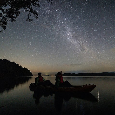 Kayakers on Rotorua lake at night under the stars during glow worm tour