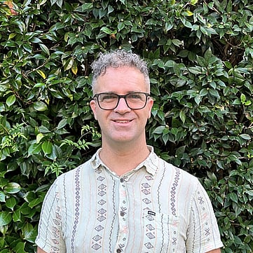 Gareth smiling at camera, greenery behind him