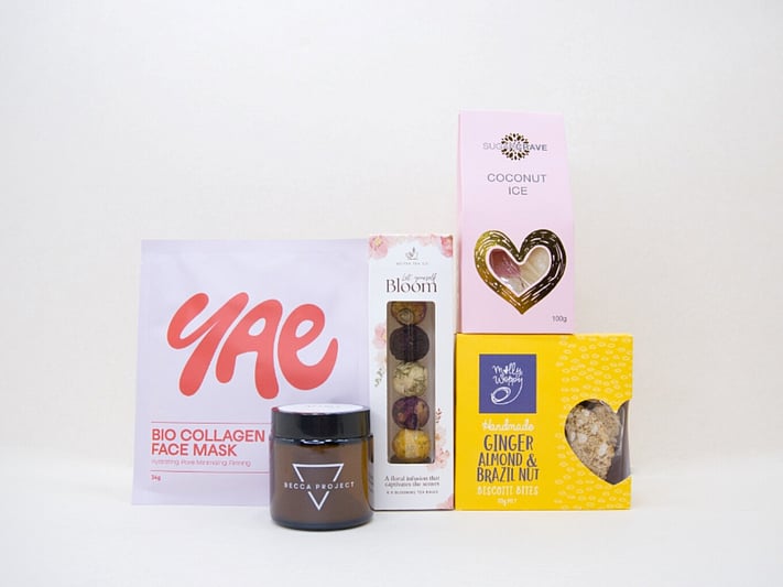 Blooming Tea Gift Box with blooming tea balls, Soleiz eye masks, Becca Project wellness products, coconut ice, and Molly Woppy treats, thoughtfully presented for tea lovers and self-care gifting.