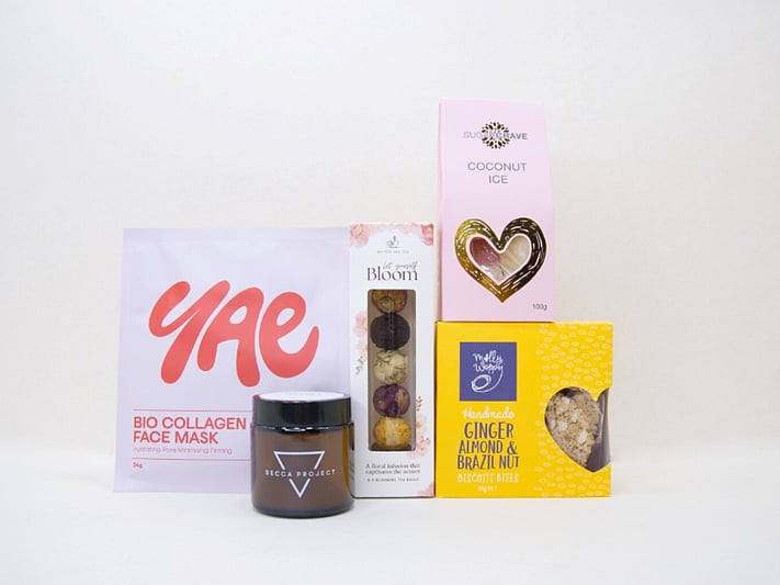 Blooming Tea Gift Box with blooming tea balls, Soleiz eye masks, Becca Project wellness products, coconut ice, and Molly Woppy treats, thoughtfully presented for tea lovers and self-care gifting.