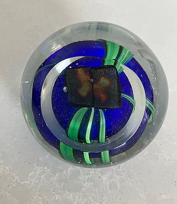 This stunning paperweight has a deep cobalt blue centre surrounded by light green ribbons and surmounted by dichroic panels all encased within clear glass. The top of which has been cut on an angle to add further interest to this fabulous art glass paperweight made by celebrated New Zealand hot glass artist Peter Viesnik. 