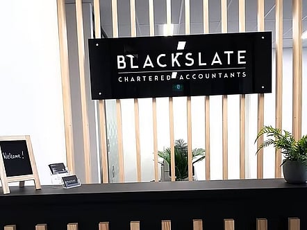 Custom digitally printed company office sign supplied and installed on a subtle standoff system to their feature bamboo slated reception divider