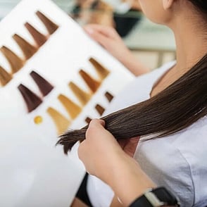 A hairdresser consulting a customer with a hair dye colour chart book
