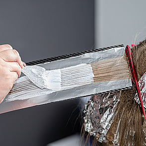 Hairdresser in the process of bleaching a womans hair