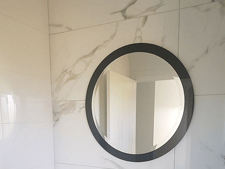 Bevelled circle mirror on a circle black splashback for 3D effect