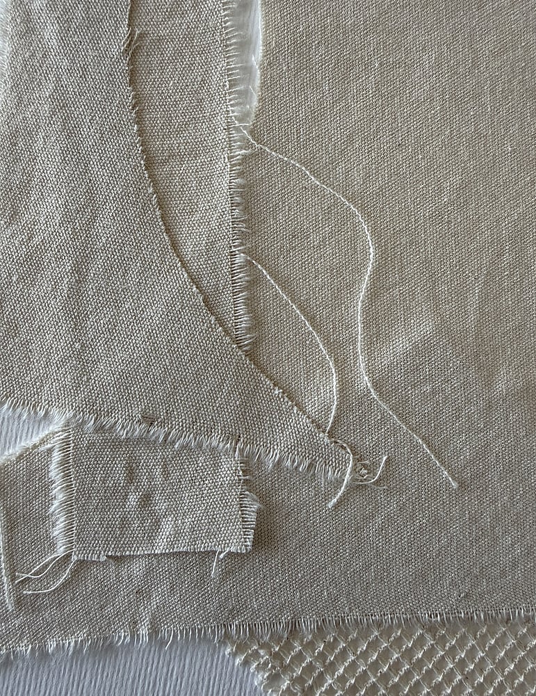detail image of layered soft honey-toned cotton fragments, showing varying weave textures, soft frayed edges and hanging threads 