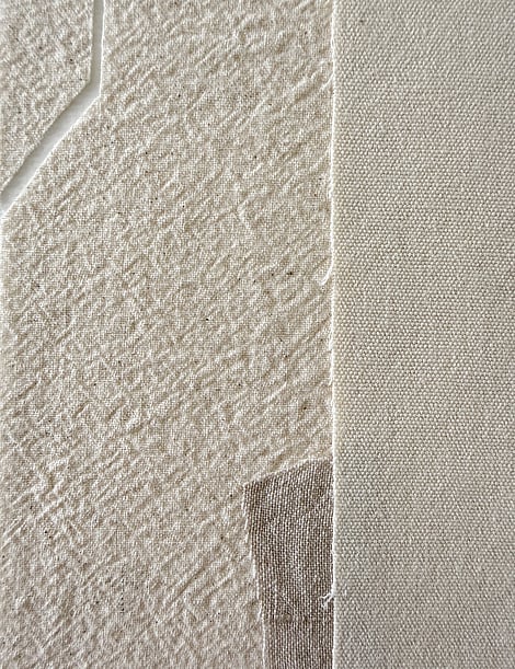 detail image of layered pale beige-toned linen and cotton fragments, showing woven texture and geometric cut-out in one linen fragment 