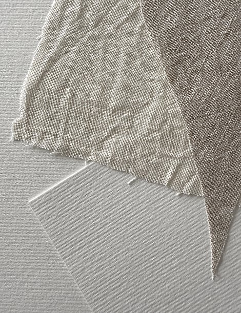 detail image of layered, beige-toned linen fragments on ivory fabriano, showing weave texture, soft frayed edges and one squared ivory fabriano paper shape 