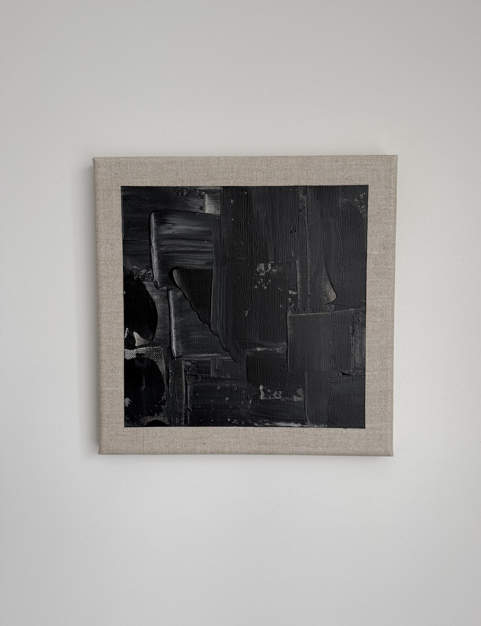 full image of a black and pale cream acrylic abstract painting on linen, showing layered painted rectangular forms, vertical drag marks and impasto passages within an exposed linen border