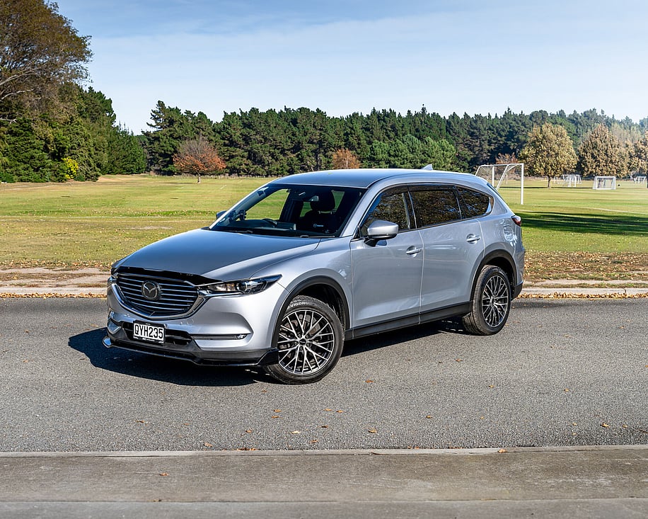 Mazda CX8 side profile parked on grass with trees behind