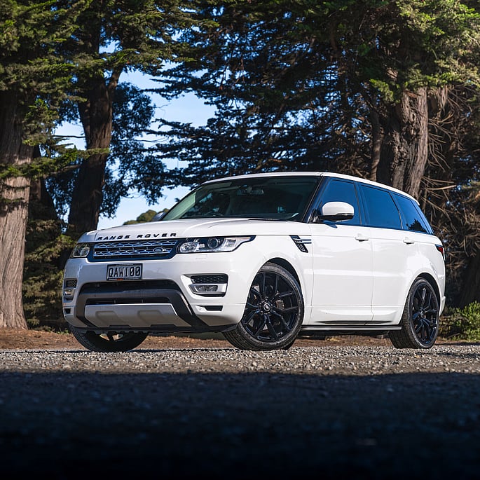 Range Rover Sport parked on gravel driveway surrounded by native trees