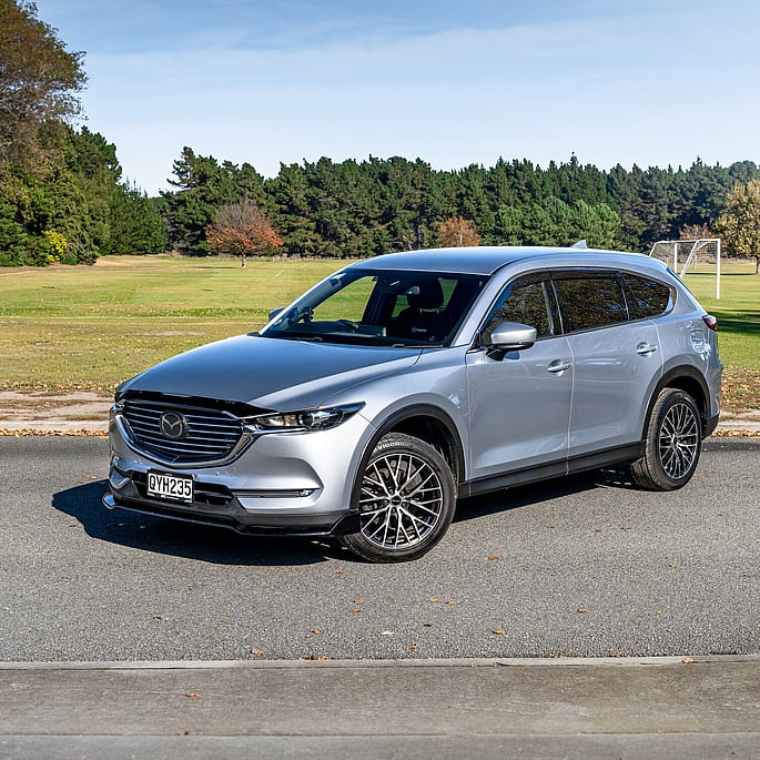 Mazda CX8 SUV parked on grass with golf course in background
