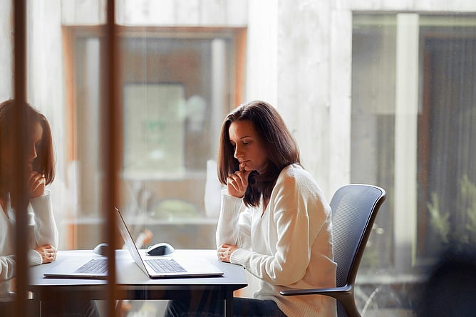 professional woman at desk looking thoughtful, ADHD masking