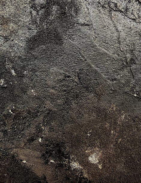 detail showing granular texture, raised ridges, matte charcoal smudging and subtle mineral sheen