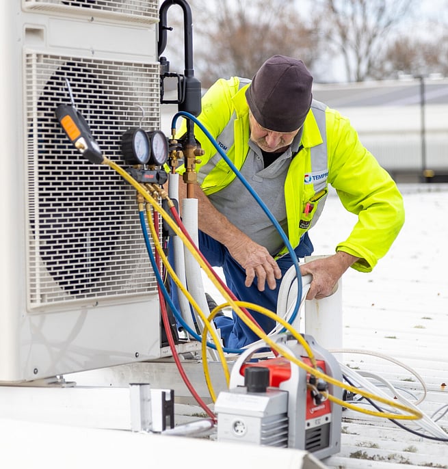 Technician installing and testing an outdoor heat pump unit