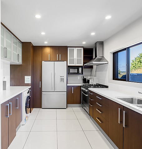 Fully equipped kitchen with dark timber cabinetry, gas stovetop, double oven, and stainless steel fridge-freezer
