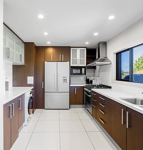 Fully equipped kitchen with dark timber cabinetry, gas stovetop, double oven, and stainless steel fridge-freezer
