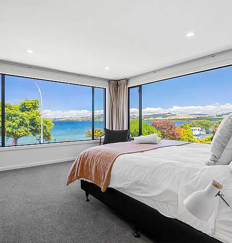 Corner bedroom with panoramic Lake Taupo views and floor-to-ceiling windows