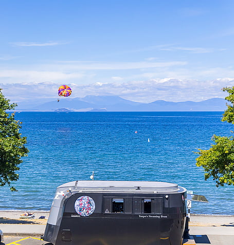 Parasailing over Lake Taupo with mountain backdrop, viewed from the property's outdoor spa area