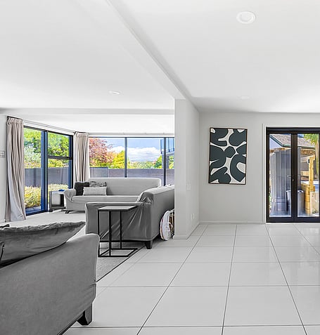 Grey sofas, abstract artwork, and tiled floor in open-plan living space with sliding doors to outdoor deck