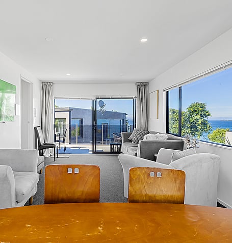 Open-plan dining area with timber table and lake views through floor-to-ceiling windows