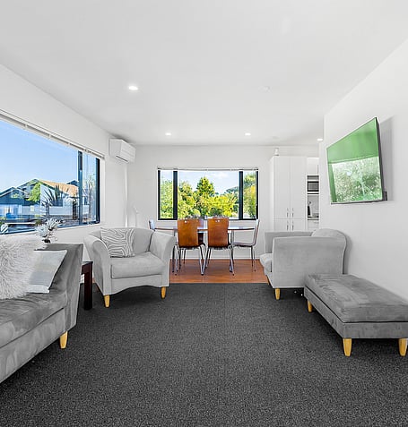 Grey sofas and dining table with chairs, overlooking Lake Taupo through corner windows