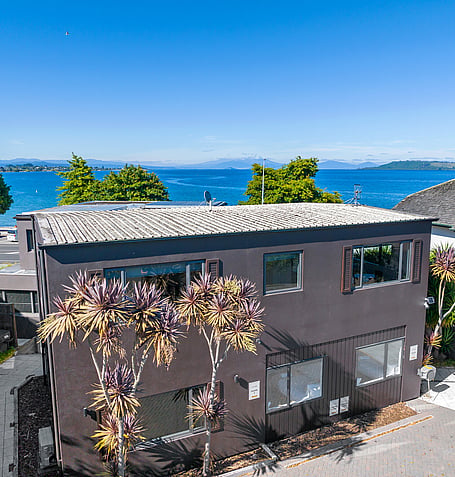 Aerial view of Gather Taupo's exterior with native plantings and lake in the background