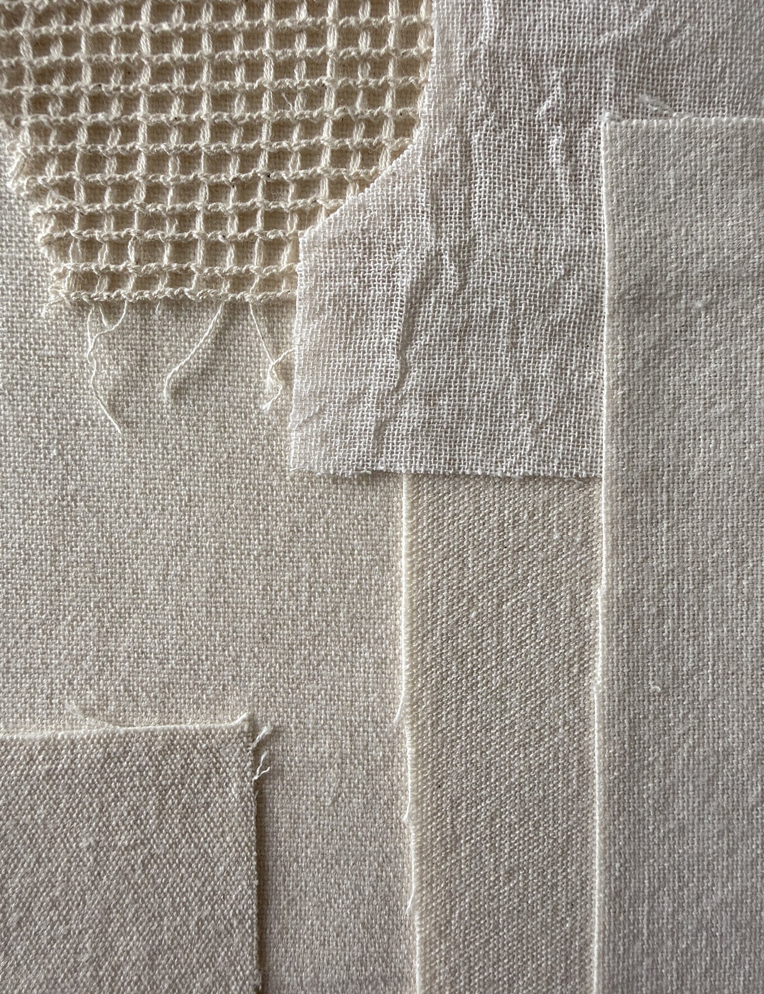 detail image of layered sand-toned linen and cotton fragments, showing varying tactile weave textures and soft frayed edges