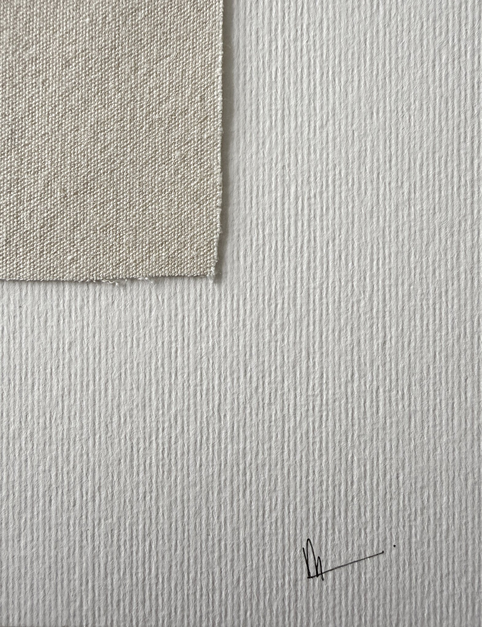 close-up image of soft white fabriano surface texture, corner of cotton fragment with soft frayed edge and handwritten signature in lower right corner