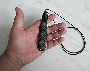 &ldquo;Pounamu (New Zealand greenstone) piece featuring a laser‑etched Patikitiki flounder pattern, showing repeating geometric diamond motifs symbolising skill, creativity, and prosperity.&rdquo;