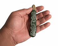 “Pounamu (New Zealand greenstone) piece with a laser‑etched kōwhaiwhai pattern of flowing, symmetrical curving motifs inspired by traditional Māori rafter designs.”