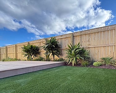 White timber fence above rock retaining wall in residential backyard