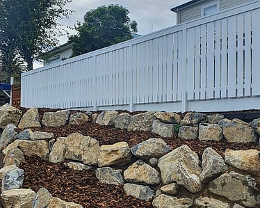 Long white timber fence along boundary with fresh landscaping