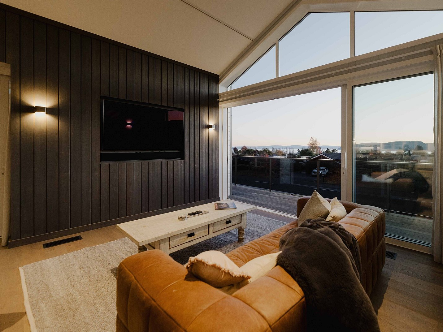 Open plan living area with dark timber feature wall and views to Lake TaupÅ