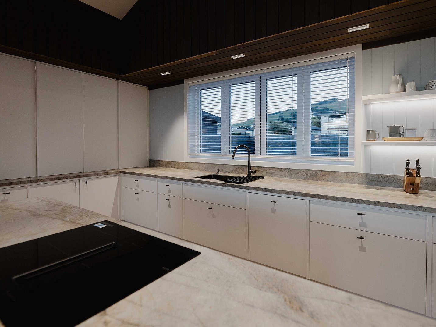 Kitchen with stone benchtop and timber bulkhead feature