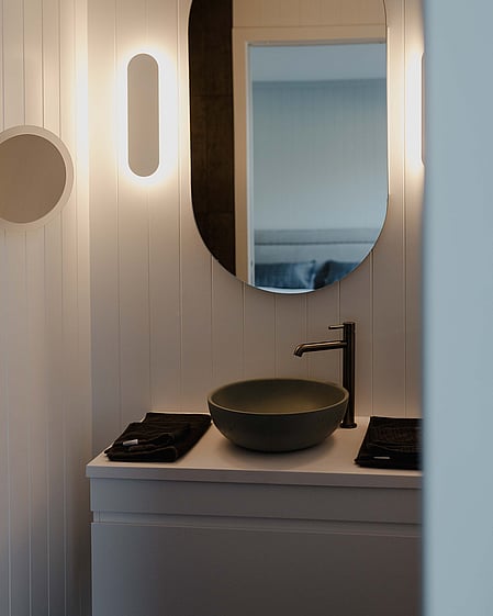 Ensuite bathroom with oval feature mirror and soft lighting