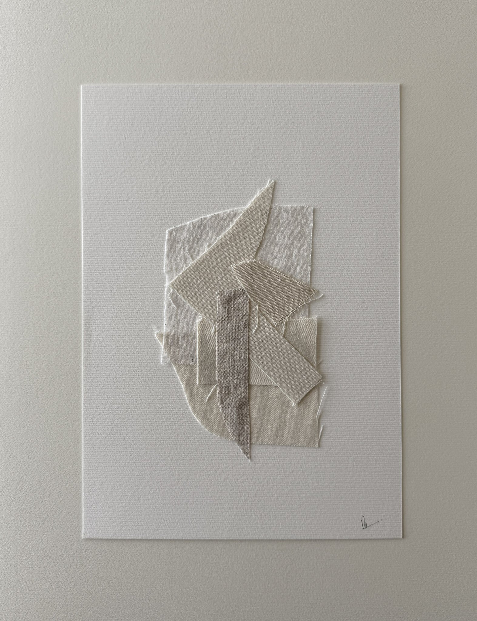 full image of layered collage of wheat-toned linen and cotton fragments on soft white fabriano, showing soft frayed edges and handwritten signature in lower right corner 