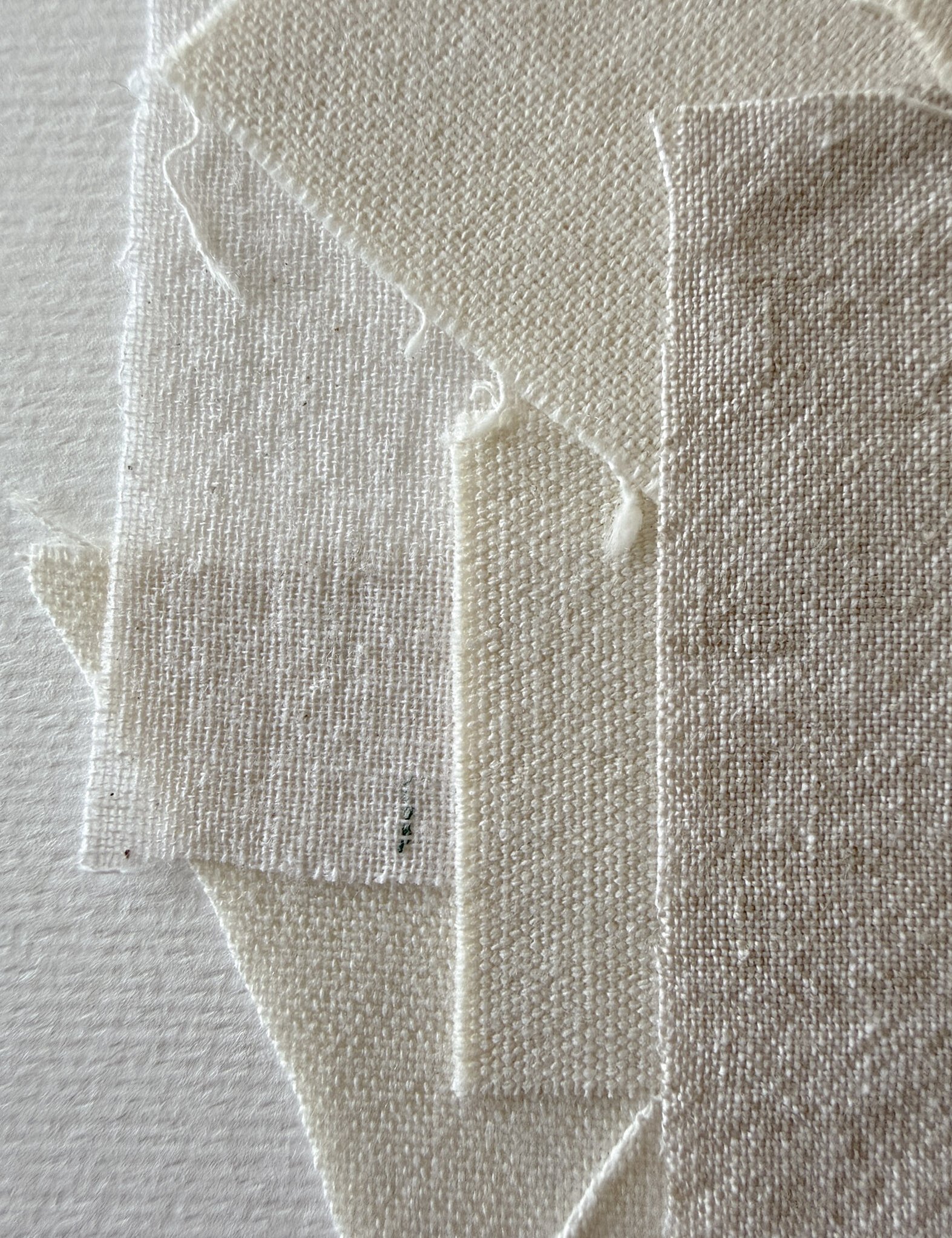 detail image of layered wheat-toned linen and cotton fragments, showing varying weave textures and soft frayed edges