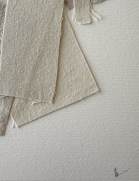 close-up image of ivory fabriano surface texture, layered cotton fragments with soft frayed edges and handwritten signature in lower right corner