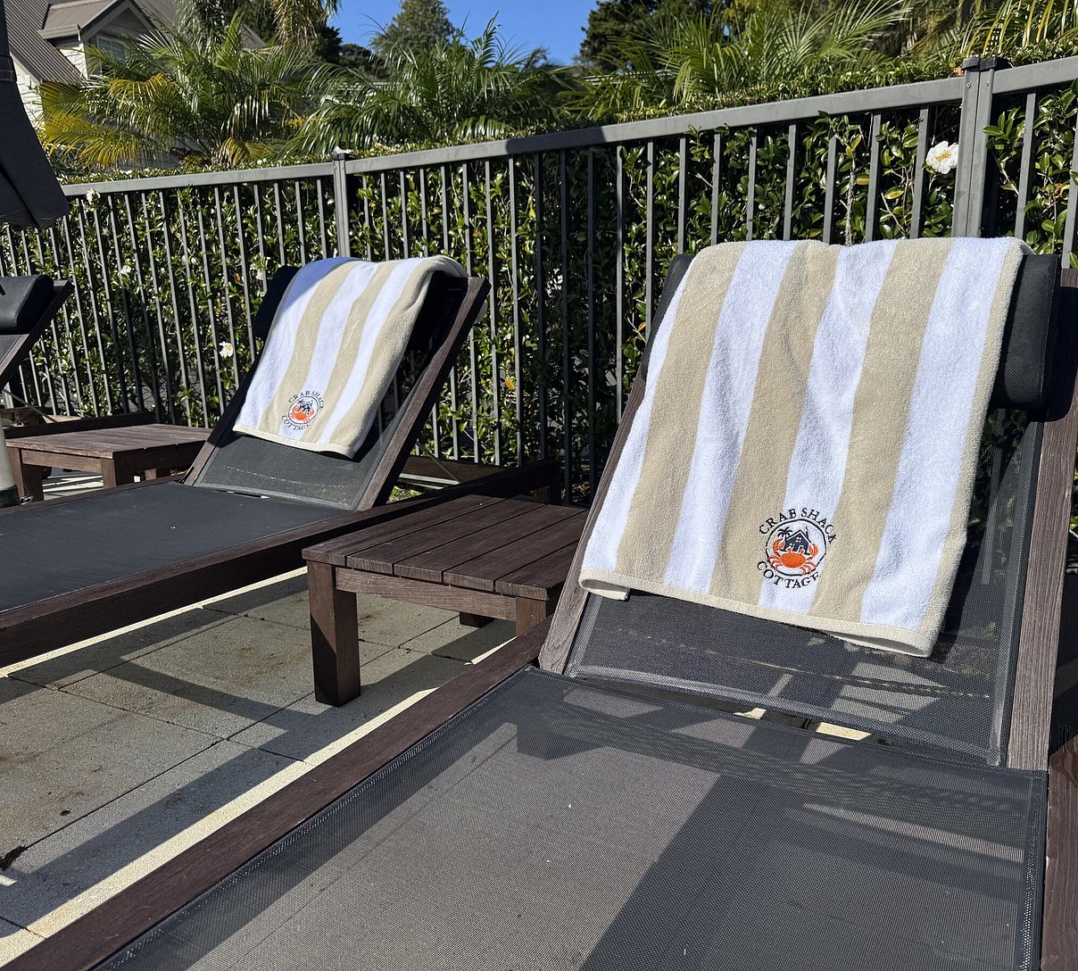 Branded Crab Shack pool towels on sun loungers beside the heated swimming pool at Russell Cottages resort