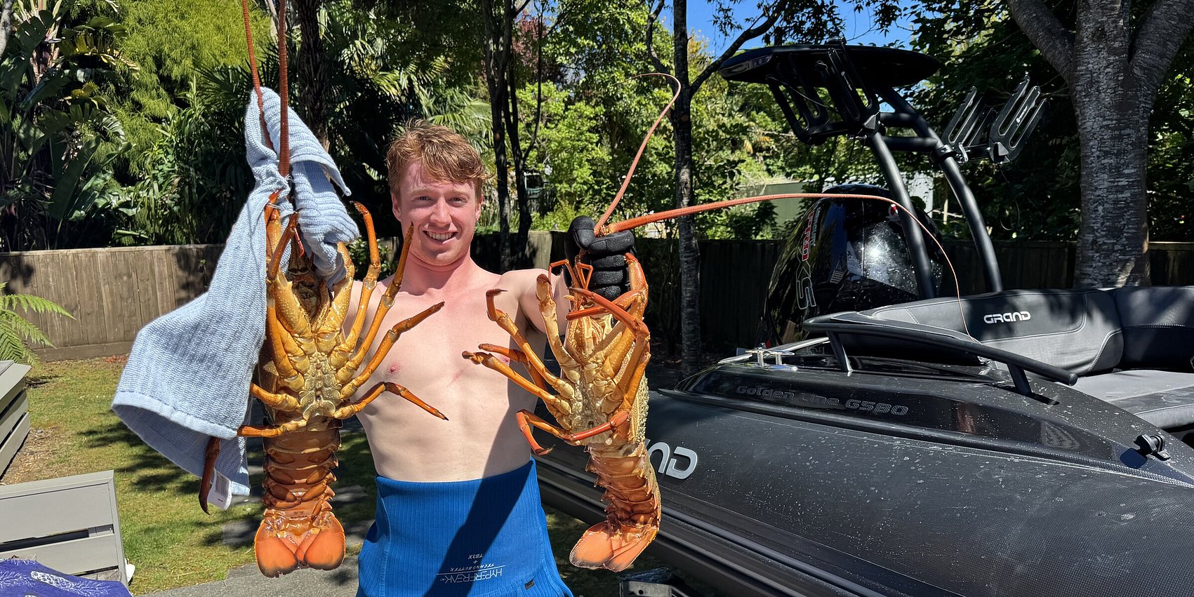Guest showcasing large caught packhorse crayfish in the garden at Crab Shack Cottage Russell