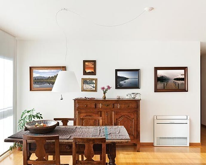 Floor-mounted heat pump in a dining room with timber furniture