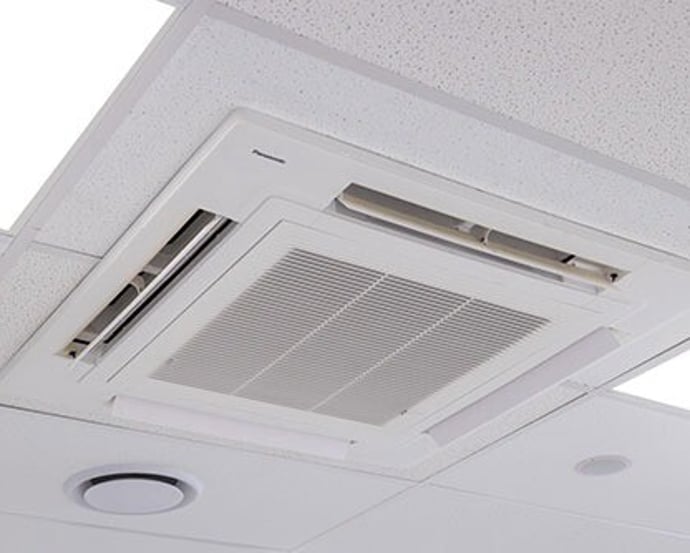 Ceiling cassette heat pump unit installed flush in a white ceiling