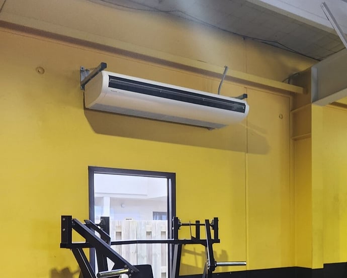 Ducted commercial air conditioning unit installed above a doorway