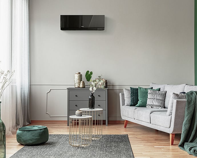 High wall heat pump mounted above a sofa in a living room