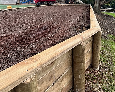 Finished timber retaining wall and leveled clay soil on residential site cut prep project.