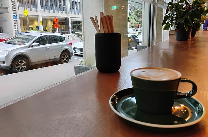 Cup of coffee on a cafe table next to a window to the street
