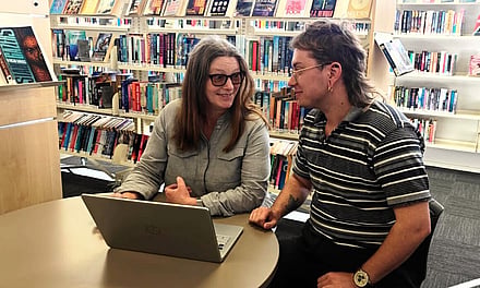 Our timebank coordinator taking a potential new member through the sign up process over a laptop in the library.